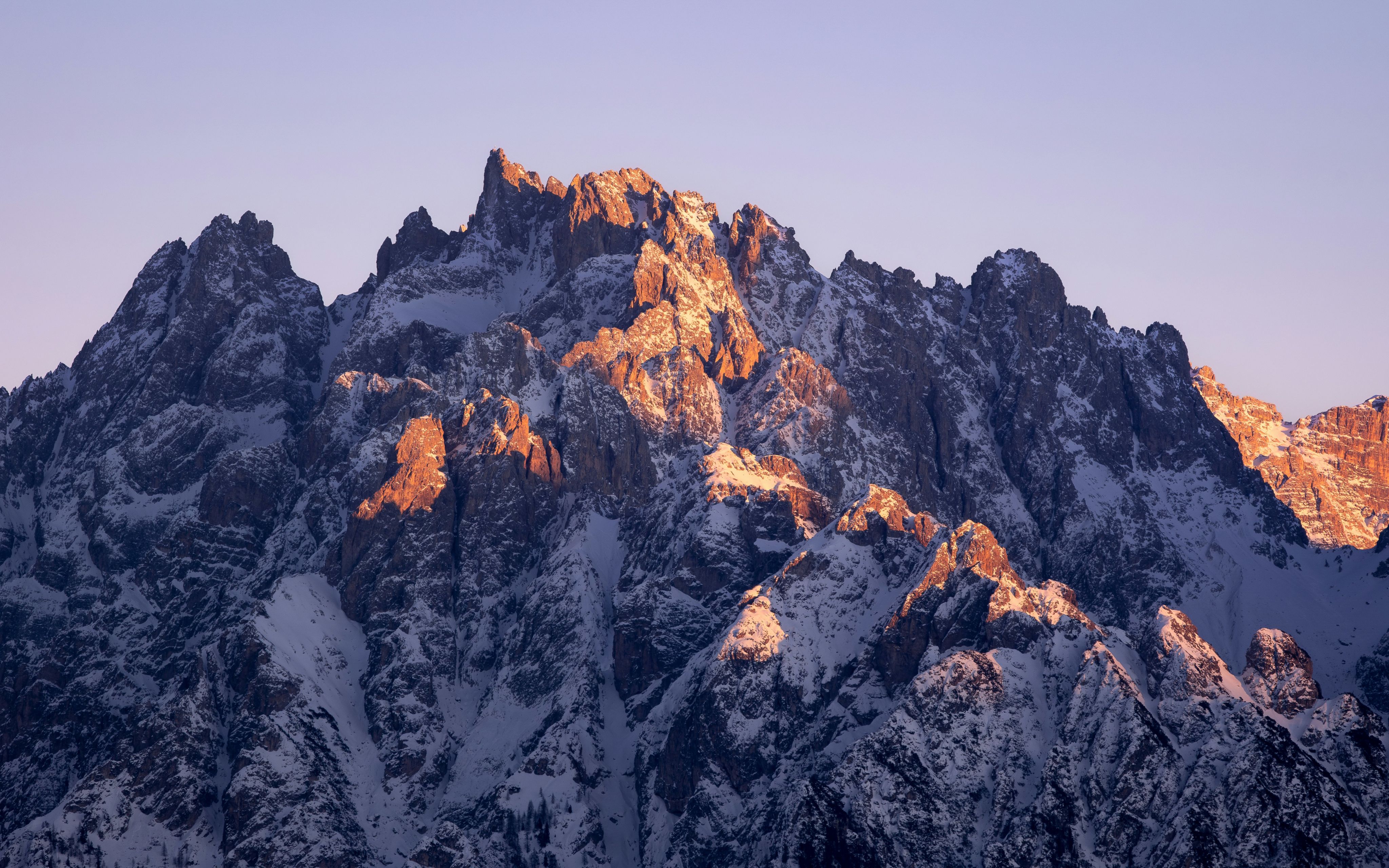 A large mountain covered in snow under a blue sky
