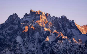 A large mountain covered in snow under a blue sky